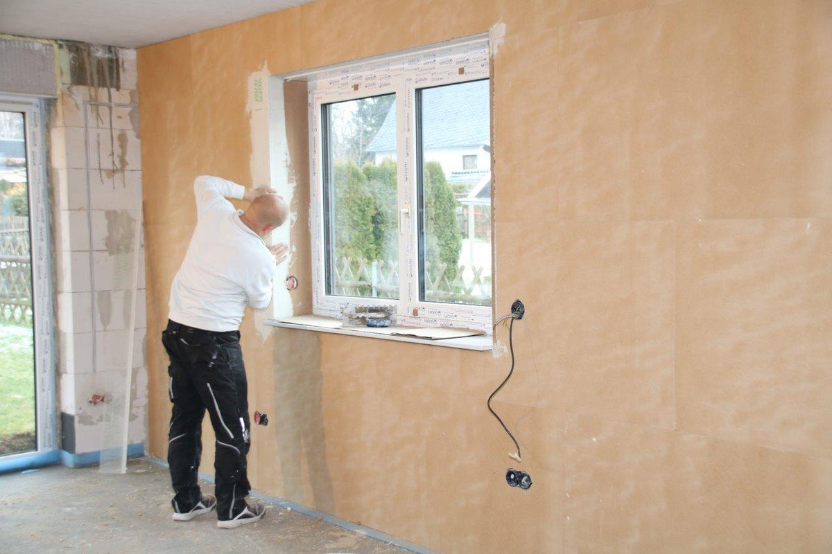 Handwerker klebt eine Eckleiste an einem Fenster im UdiIN 2CM System