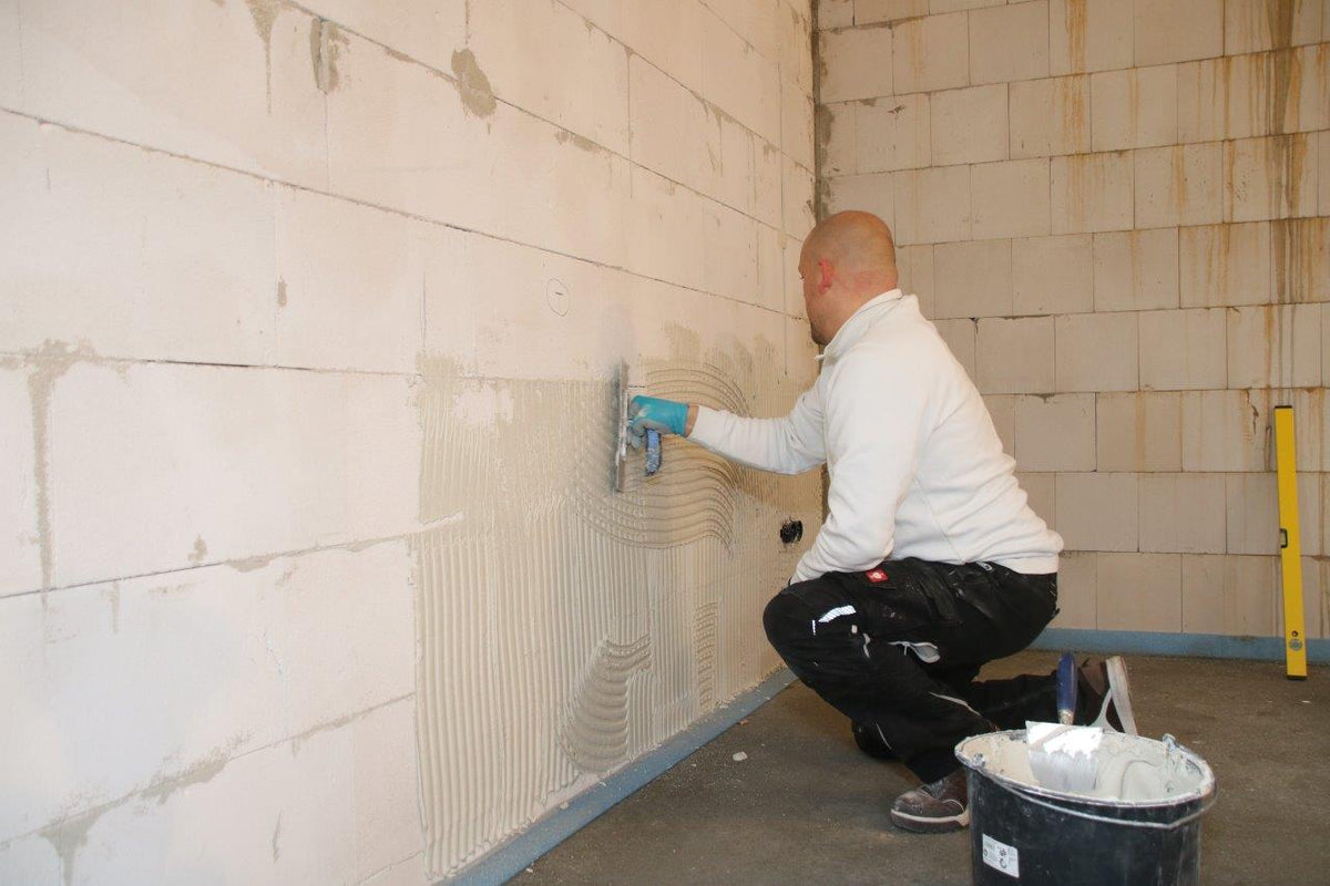 Handwerker verputzt eine Wand als Vorbereitung für die UdiIN 2CM Innendämmung