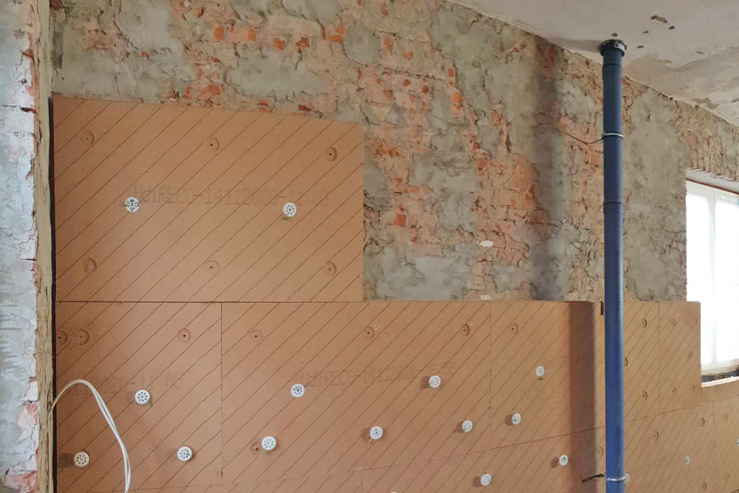 Teilweise mit UdiIN RECO Dämmelementen belegte Wand während der Sanierung